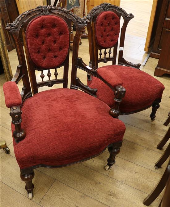 A pair of late Victorian walnut ladys and gentlemans armchairs, upholstered in buttoned red dralon